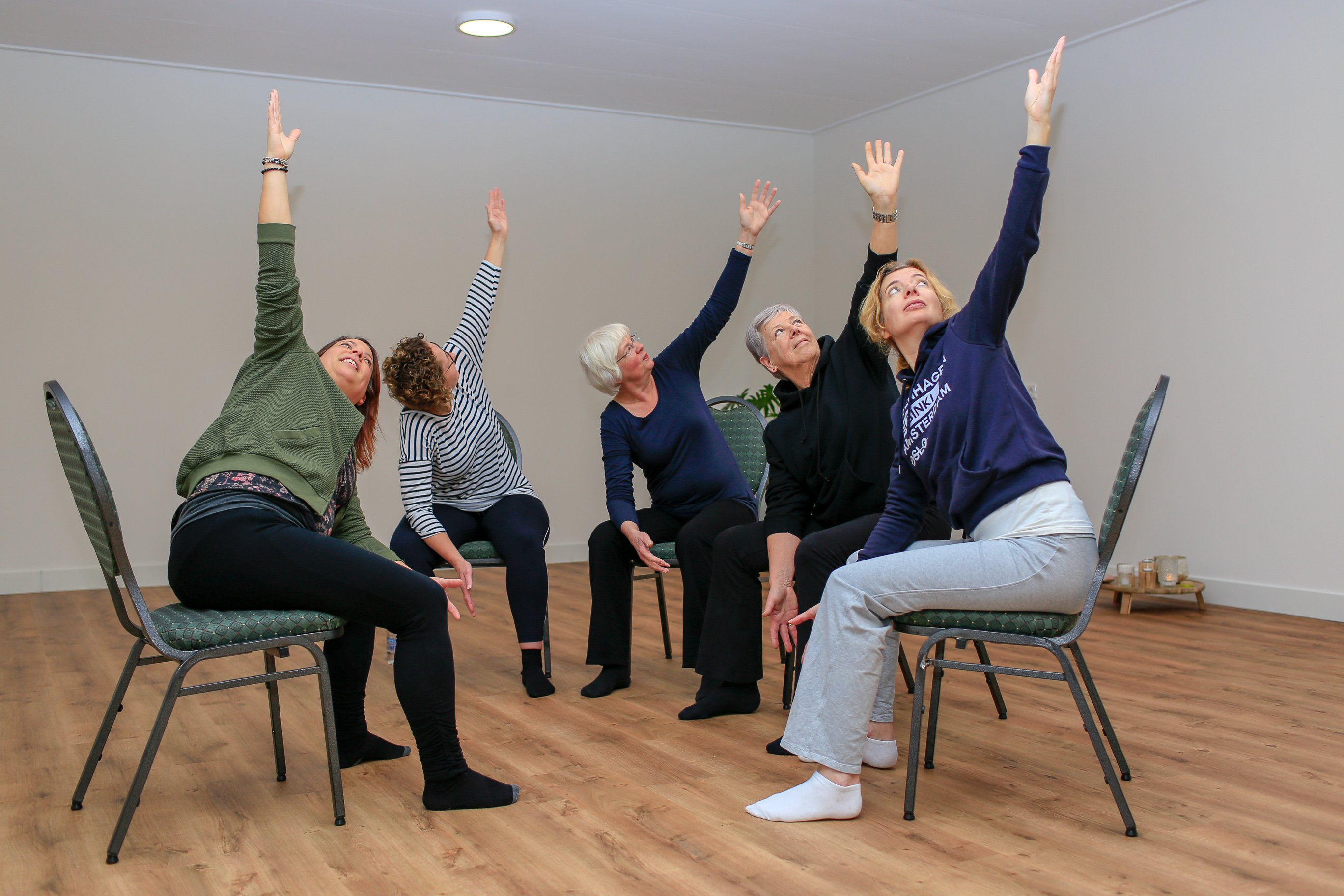 Vrouwen die yoga doen op stoelen