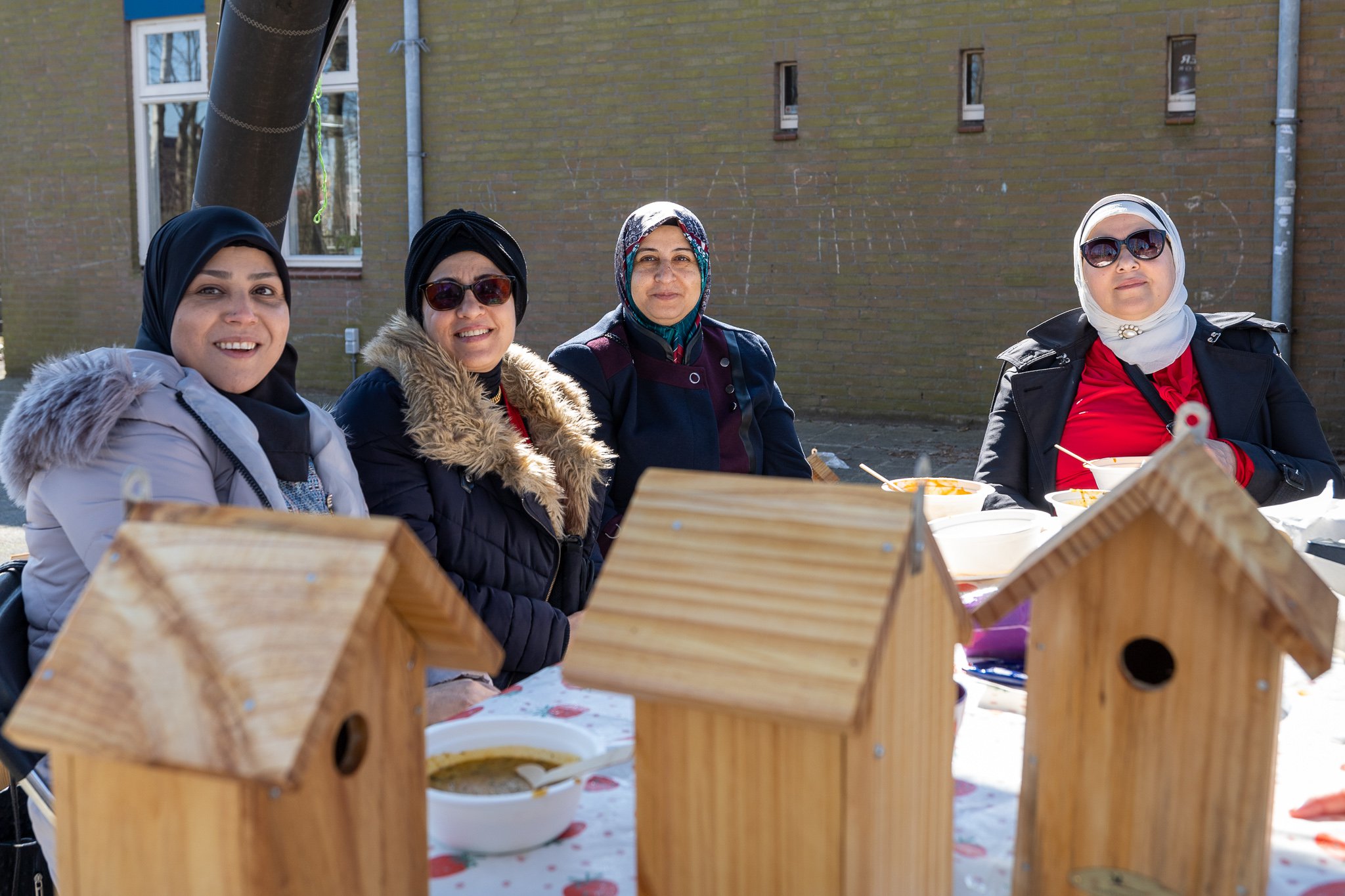 Vier vrouwen poseren trots achter de zelf gemaakte vogelhuisjes