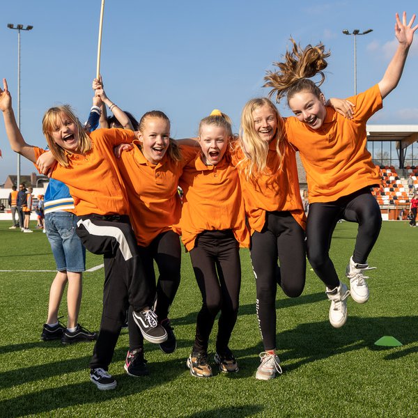 Een groepje meiden in Oranje op een sportveld.